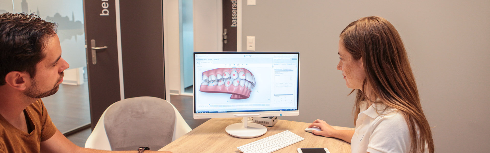 Eine Zahnärztin in Bern erklärt einem Patienten die Funktionsweise von Invisalign